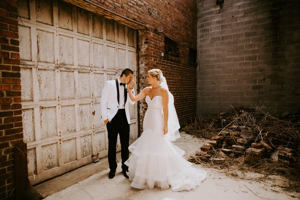 Bride & Groom staged in front of industrial and grungy garage door for pictures. 
