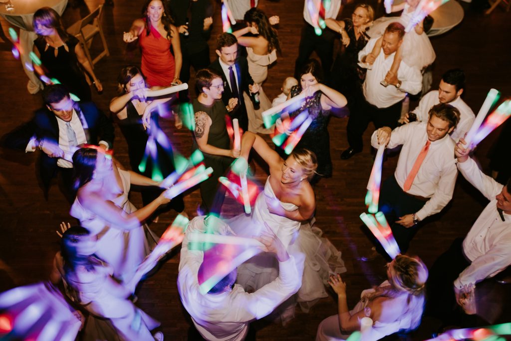 Guests dance the night away with neon foam sticks for an amazingly fun picture at the wedding reception.